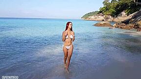 Naga ruda dziewczyna cieszy się słoneczną kąpielą na publicznej plaży