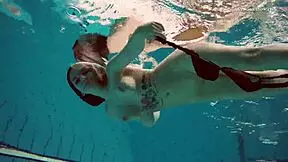 Dashka enjoys a beautiful swim in the pool, showcasing her brunette hair and nude body