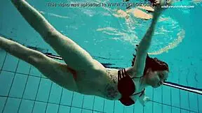 Dashka enjoys a beautiful swim in the pool, showcasing her brunette hair and nude body