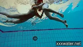 Milana and Katrin tease each other by ripping bikinis off in the pool. They swim nude underwater in softcore fun.