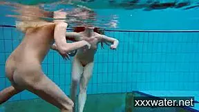 Milana and Katrin tease each other by ripping bikinis off in the pool. They swim nude underwater in softcore fun.