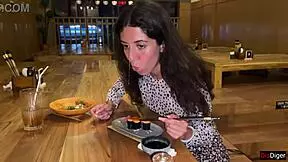 a girl eats sushi rolls in a bar